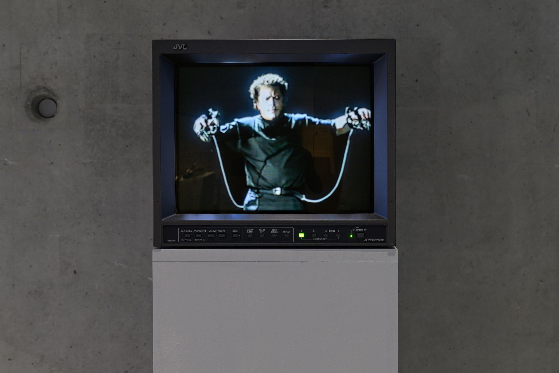 CRT monitor on plinth at museum showing Michel Waisvisz performing with 'The Hands' artwork.